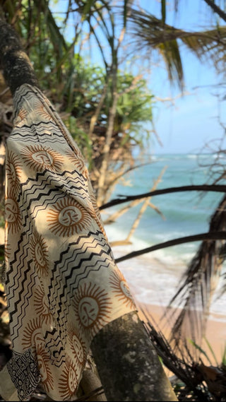Sarong with yellow sun print drapped over a tropical tree
